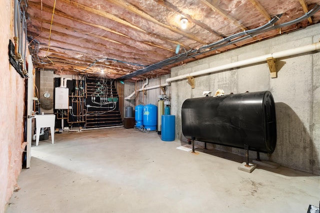 unfinished below grade area featuring water heater, a sink, and heating fuel