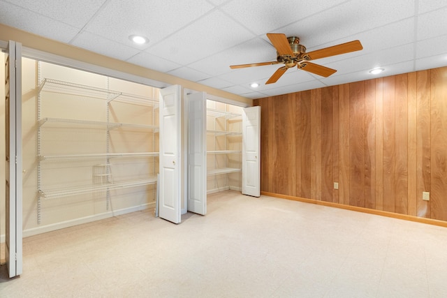 unfurnished bedroom featuring a ceiling fan, wood walls, two closets, and tile patterned floors