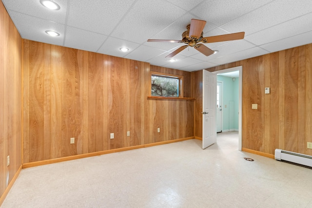 spare room with wooden walls, baseboards, a baseboard radiator, ceiling fan, and light floors