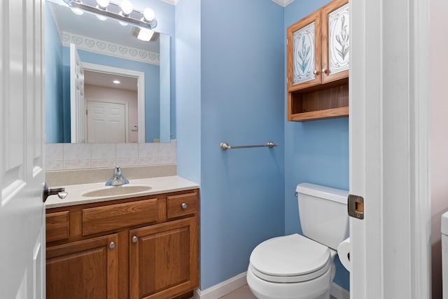 bathroom with toilet, tasteful backsplash, vanity, and baseboards