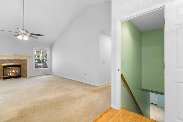 unfurnished living room with light carpet, baseboards, lofted ceiling, ceiling fan, and a premium fireplace