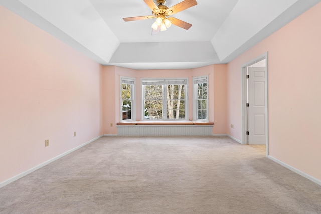 unfurnished room featuring baseboards, ceiling fan, a raised ceiling, and light colored carpet