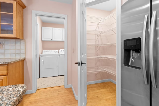 washroom featuring light wood-type flooring, cabinet space, baseboards, and washer and dryer