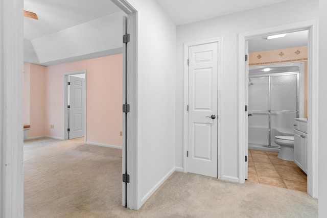 corridor featuring baseboards and light colored carpet