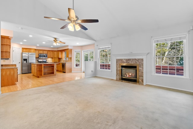 unfurnished living room with baseboards, light colored carpet, a premium fireplace, vaulted ceiling, and recessed lighting