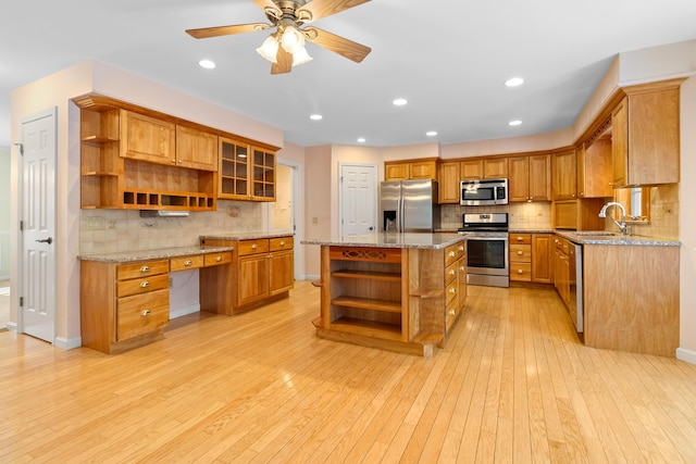 kitchen featuring glass insert cabinets, appliances with stainless steel finishes, a center island, open shelves, and built in desk