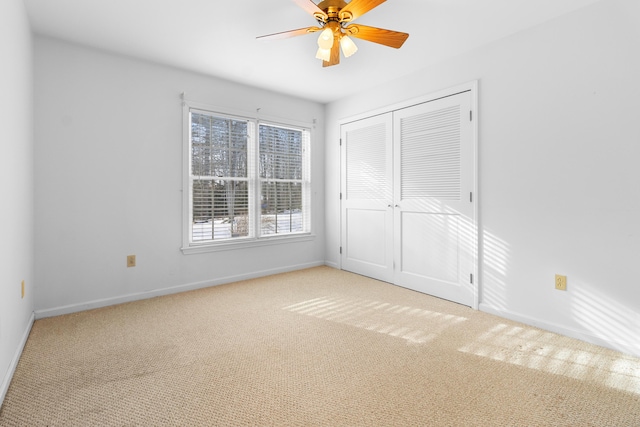 unfurnished bedroom featuring baseboards, a closet, a ceiling fan, and light colored carpet