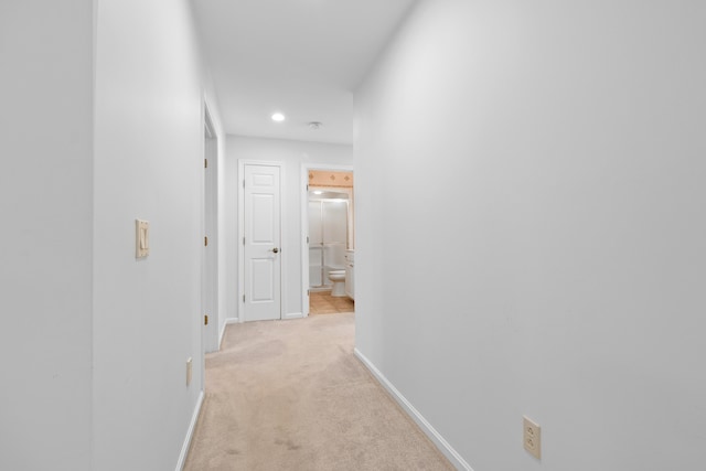 hallway with recessed lighting, light colored carpet, and baseboards