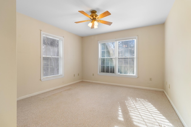 spare room featuring ceiling fan, light carpet, and baseboards