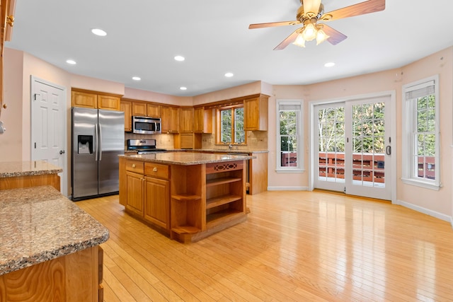 kitchen with light stone counters, brown cabinets, light wood finished floors, open shelves, and stainless steel appliances