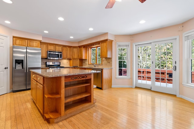 kitchen with light wood-style flooring, stainless steel appliances, a kitchen island, brown cabinets, and open shelves