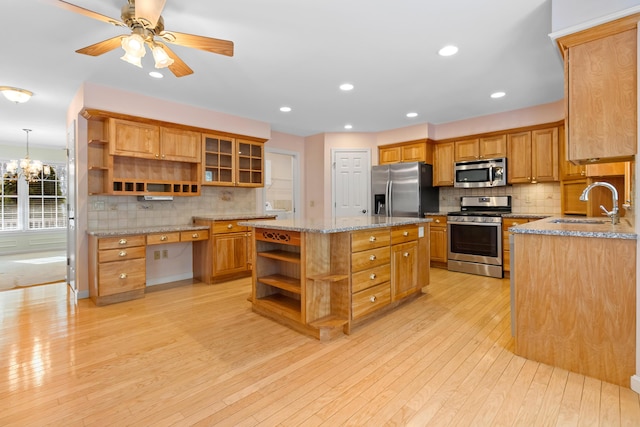 kitchen featuring open shelves, appliances with stainless steel finishes, glass insert cabinets, a kitchen island, and a sink