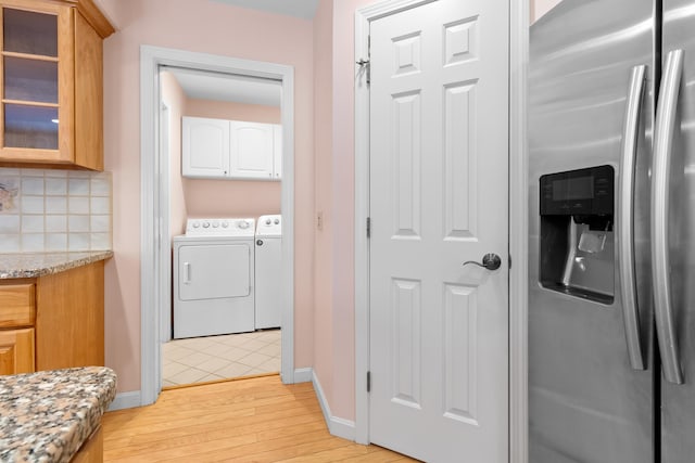 laundry area with light wood-type flooring, cabinet space, baseboards, and separate washer and dryer