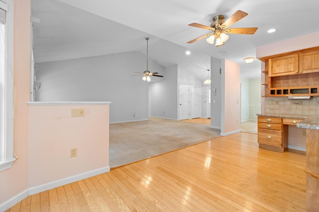 kitchen featuring ceiling fan, light wood-style flooring, vaulted ceiling, built in study area, and backsplash