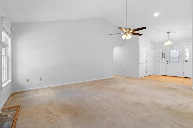 unfurnished living room featuring baseboards, vaulted ceiling, a ceiling fan, and light colored carpet