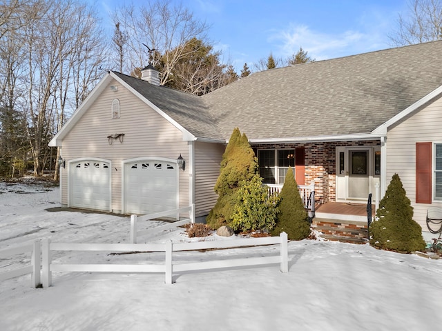 view of front facade with a shingled roof, a chimney, an attached garage, and brick siding