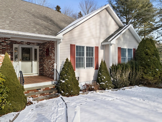 view of front facade featuring brick siding and roof with shingles