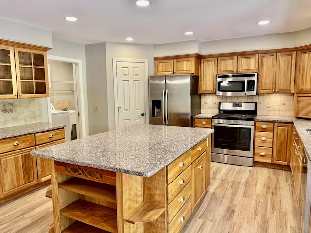 18 Patricia Ln, Saint George, ME 04859 - kitchen featuring appliances with stainless steel finishes, open shelves, light wood-type flooring, tasteful backsplash, and brown cabinetry