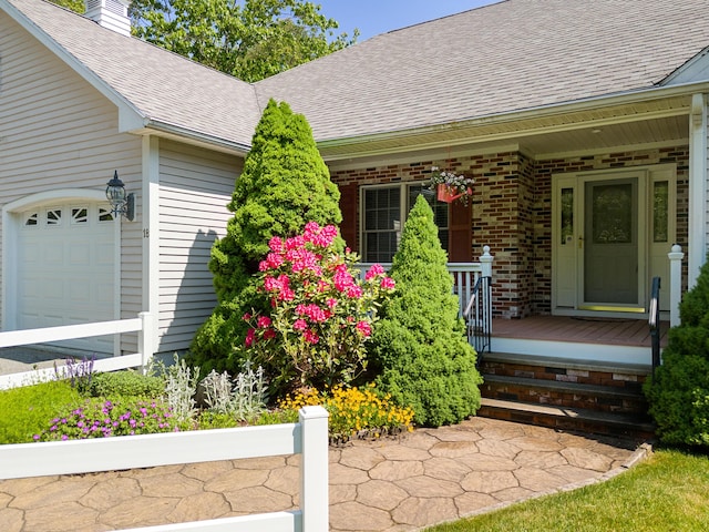 18 Patricia Ln, Saint George, ME 04859 - property entrance featuring a porch, roof with shingles, brick siding, a chimney, and an attached garage