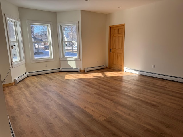 spare room with wood-type flooring and a baseboard heating unit