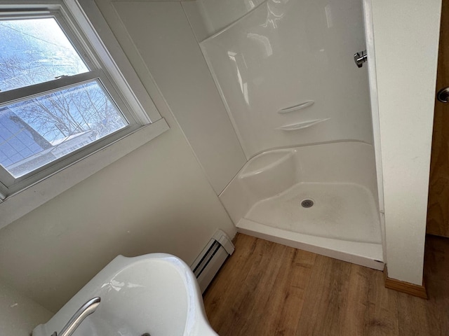 bathroom with wood-type flooring, a shower, and a baseboard heating unit