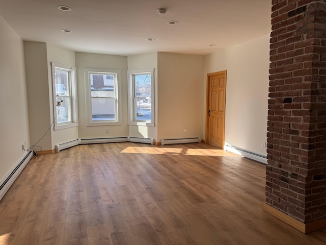 empty room with hardwood / wood-style floors and a baseboard heating unit