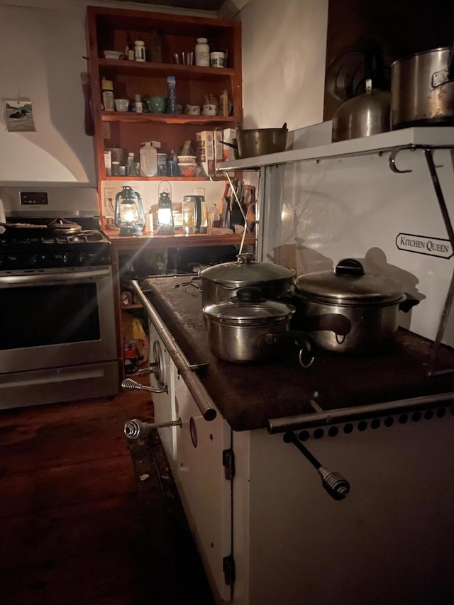 kitchen featuring stainless steel range with gas cooktop, white cabinetry, and dark countertops