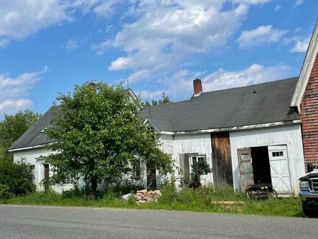 view of front of house featuring an attached garage, a shingled roof, and a chimney