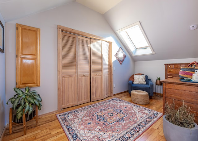 sitting room featuring lofted ceiling with skylight and light wood-type flooring