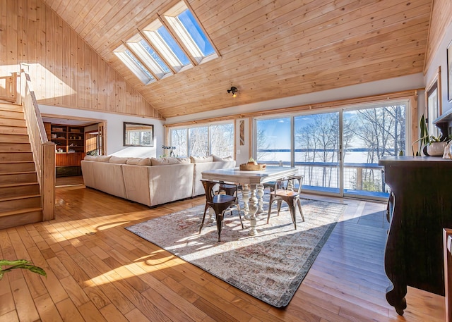 dining room featuring high vaulted ceiling, wood ceiling, light hardwood / wood-style floors, and a skylight