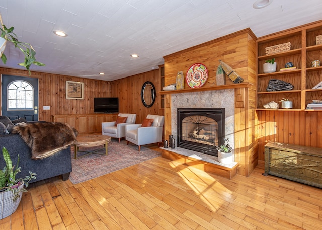 living room with wooden walls, a fireplace, and light hardwood / wood-style floors