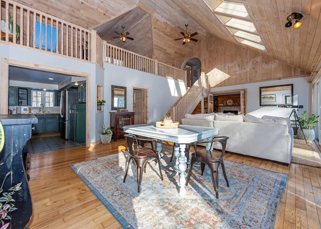 dining area with wooden ceiling, a skylight, high vaulted ceiling, and light wood-type flooring