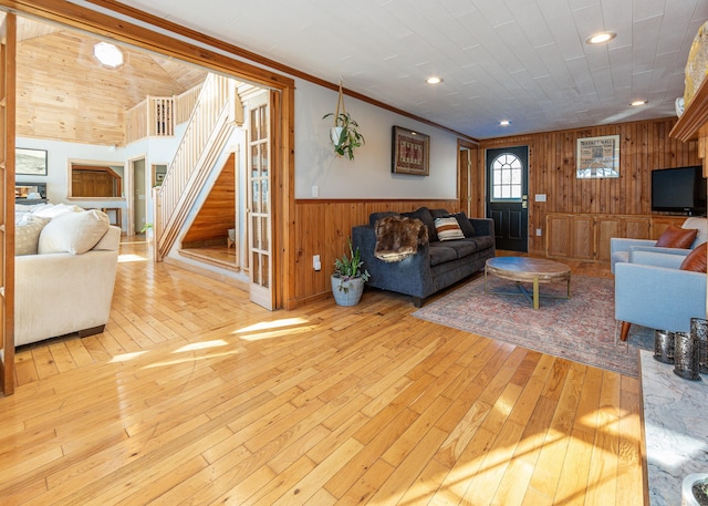 living room featuring wood ceiling, ornamental molding, wooden walls, and light wood-type flooring