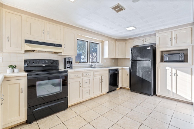 kitchen with tile countertops, sink, backsplash, light tile patterned floors, and black appliances