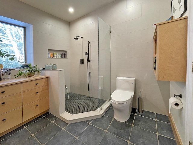 bathroom with tile patterned flooring, a tile shower, tile walls, and toilet