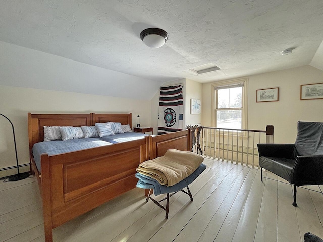 bedroom with vaulted ceiling, light hardwood / wood-style floors, and a textured ceiling