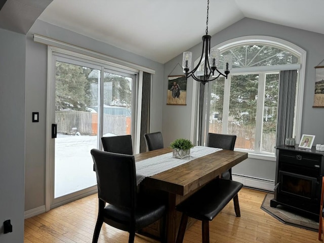 dining space with lofted ceiling, light hardwood / wood-style floors, an inviting chandelier, and baseboard heating