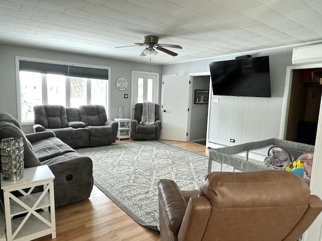 living room featuring hardwood / wood-style flooring, an AC wall unit, and ceiling fan