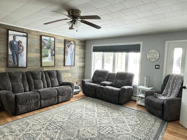 living room featuring hardwood / wood-style floors, wood walls, ceiling fan, and baseboard heating