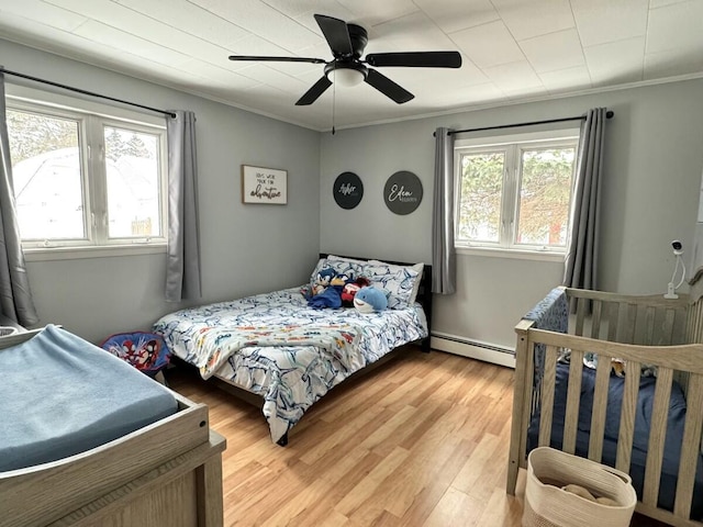 bedroom with crown molding, a baseboard radiator, ceiling fan, and hardwood / wood-style floors