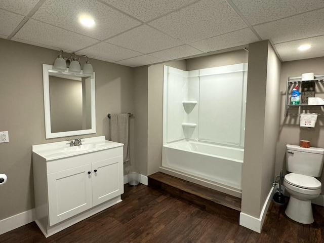 full bathroom featuring hardwood / wood-style floors, vanity, toilet, tub / shower combination, and a drop ceiling