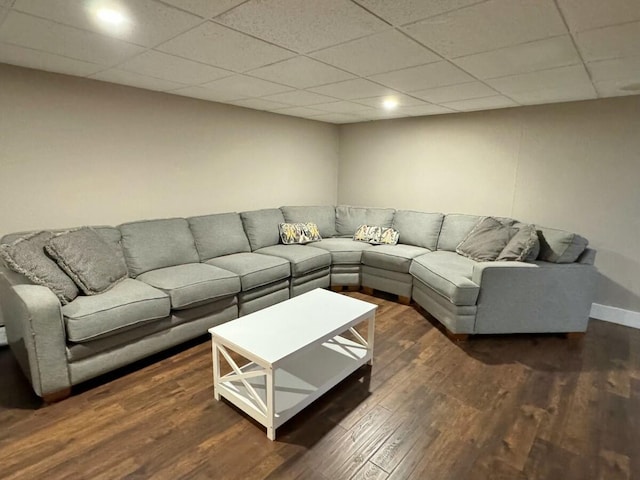 living room featuring dark wood-type flooring and a paneled ceiling