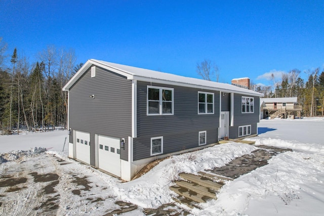 snow covered back of property with a garage