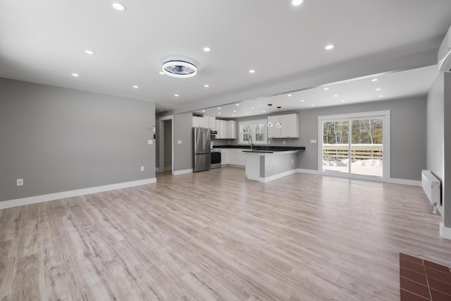 unfurnished living room featuring radiator, sink, and light hardwood / wood-style flooring