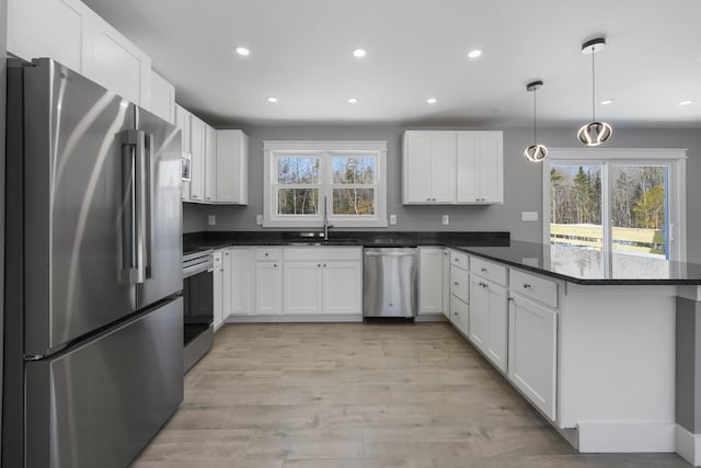 kitchen with white cabinetry, appliances with stainless steel finishes, sink, and decorative light fixtures