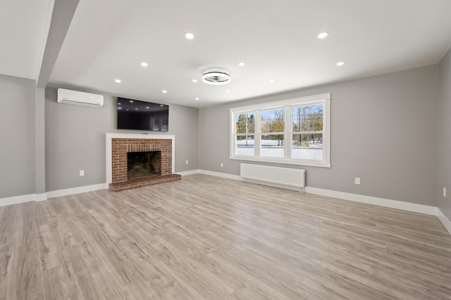 unfurnished living room with radiator, a fireplace, light hardwood / wood-style floors, and an AC wall unit