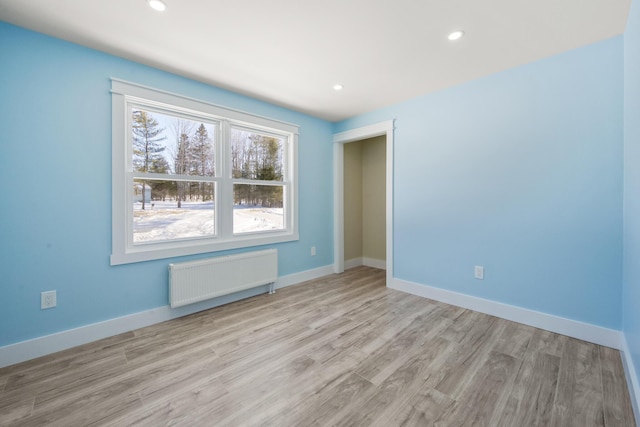 empty room featuring radiator heating unit and light hardwood / wood-style floors