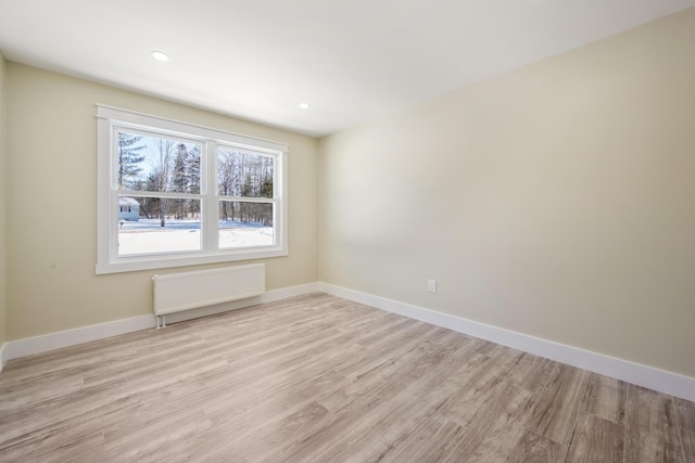 unfurnished room featuring light hardwood / wood-style flooring and radiator heating unit