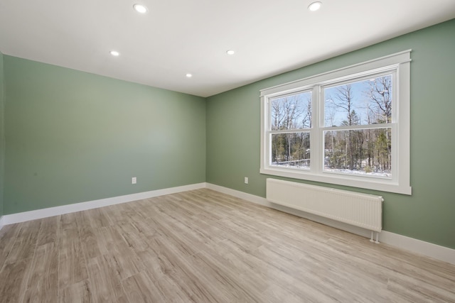 spare room with radiator and light wood-type flooring