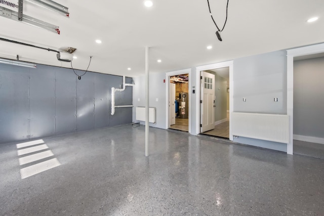 garage featuring a garage door opener, radiator, and water heater